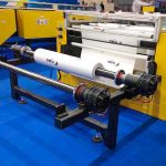 Bobina de plástico imprimiéndose. En los extremos del eje se ven los soportes de seguridad